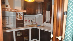 A compact kitchen with wooden cabinets, a tiled backsplash, and a small sink.