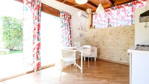Eine helle Küche mit Holzboden, weißen Schränken und einem Essbereich mit weißem Tisch und Stühlen.