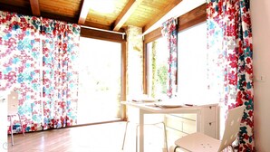Ein Zimmer mit Holzboden, einem Tisch mit Stühlen und blumigen Vorhängen.