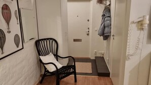 A hallway with a black chair, a coat rack with a jacket, and a door with a mailbox. - Charming Apartment in the Heart of Stockholm! (Stockholm)
