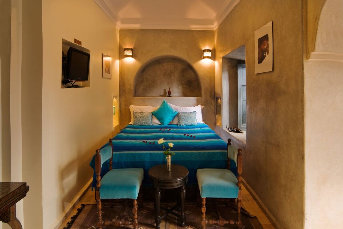 A bedroom with a large bed, two bedside tables, and two chairs.