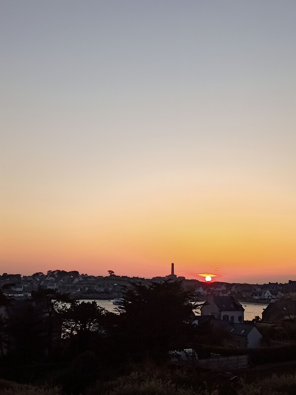 A sunset over a town with buildings and a river.