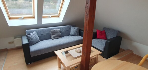 A modern living room with a grey sofa, a small wooden coffee table, and a skylight above.