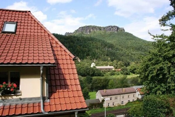 A house with a red-tiled roof, a small window with a view of a mountain, and a balcony with flowers. - Vacation apartment for 4 people 38 m² with a view of the Lilienstein (Königstein)
