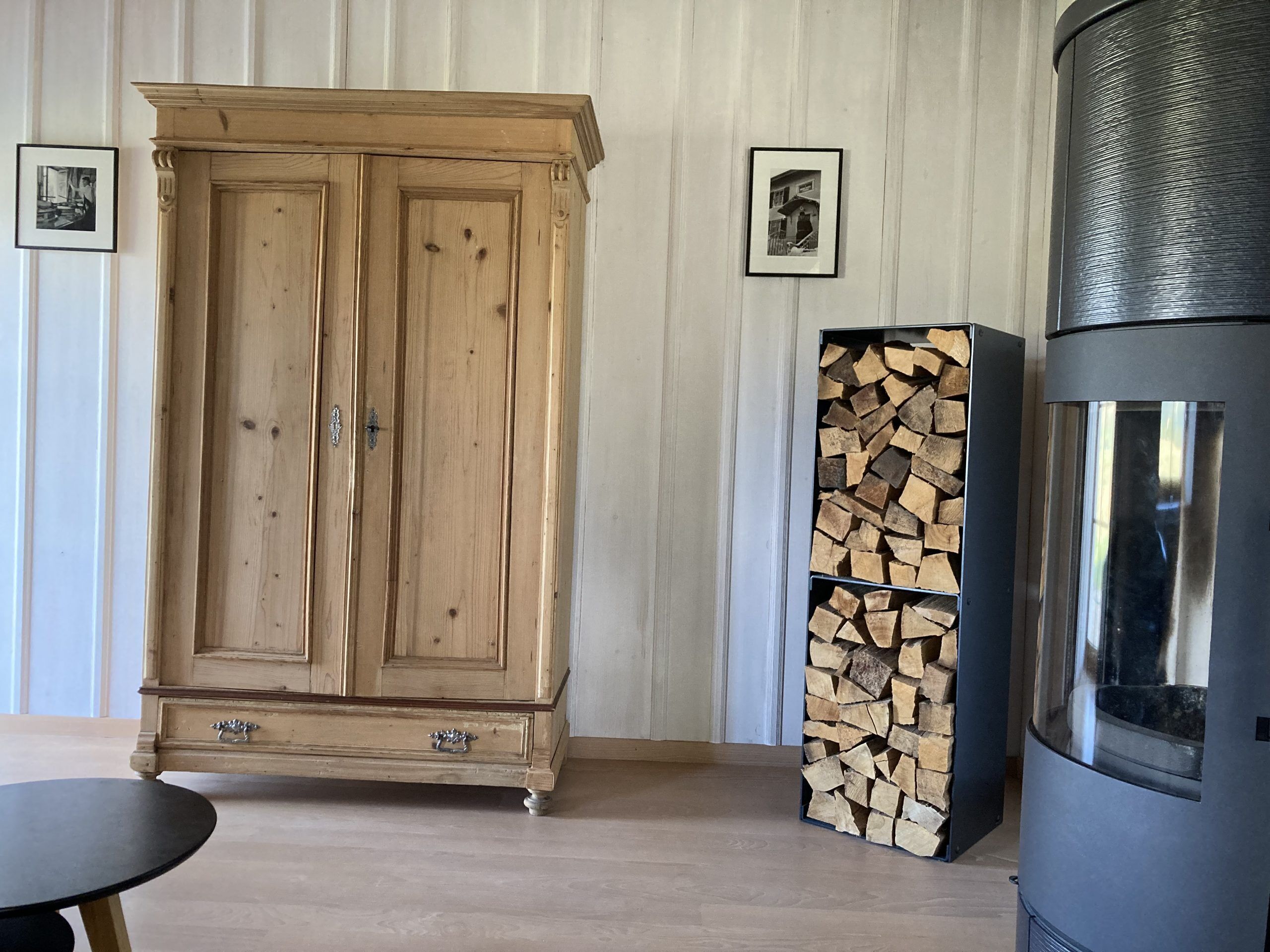 A wooden wardrobe, a stack of firewood, and a wood-burning stove.