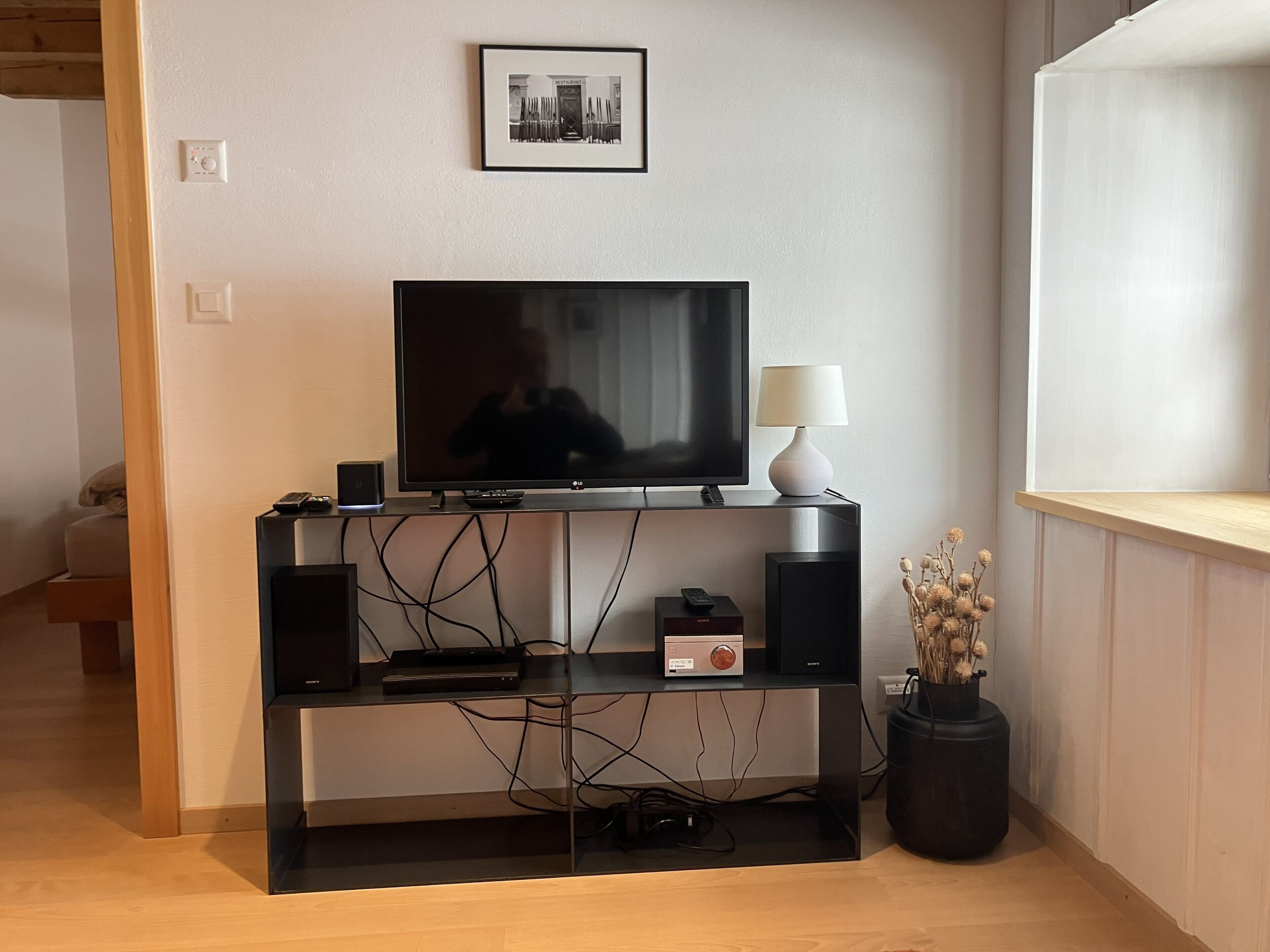 A modern living room with a flat-screen TV, a sound system, and a lamp on a wooden entertainment unit.