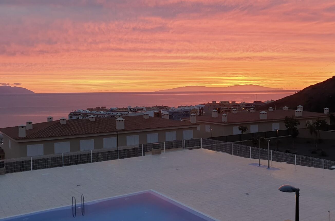 Zona de piscina al terrat amb vista a una població costanera al capvespre.