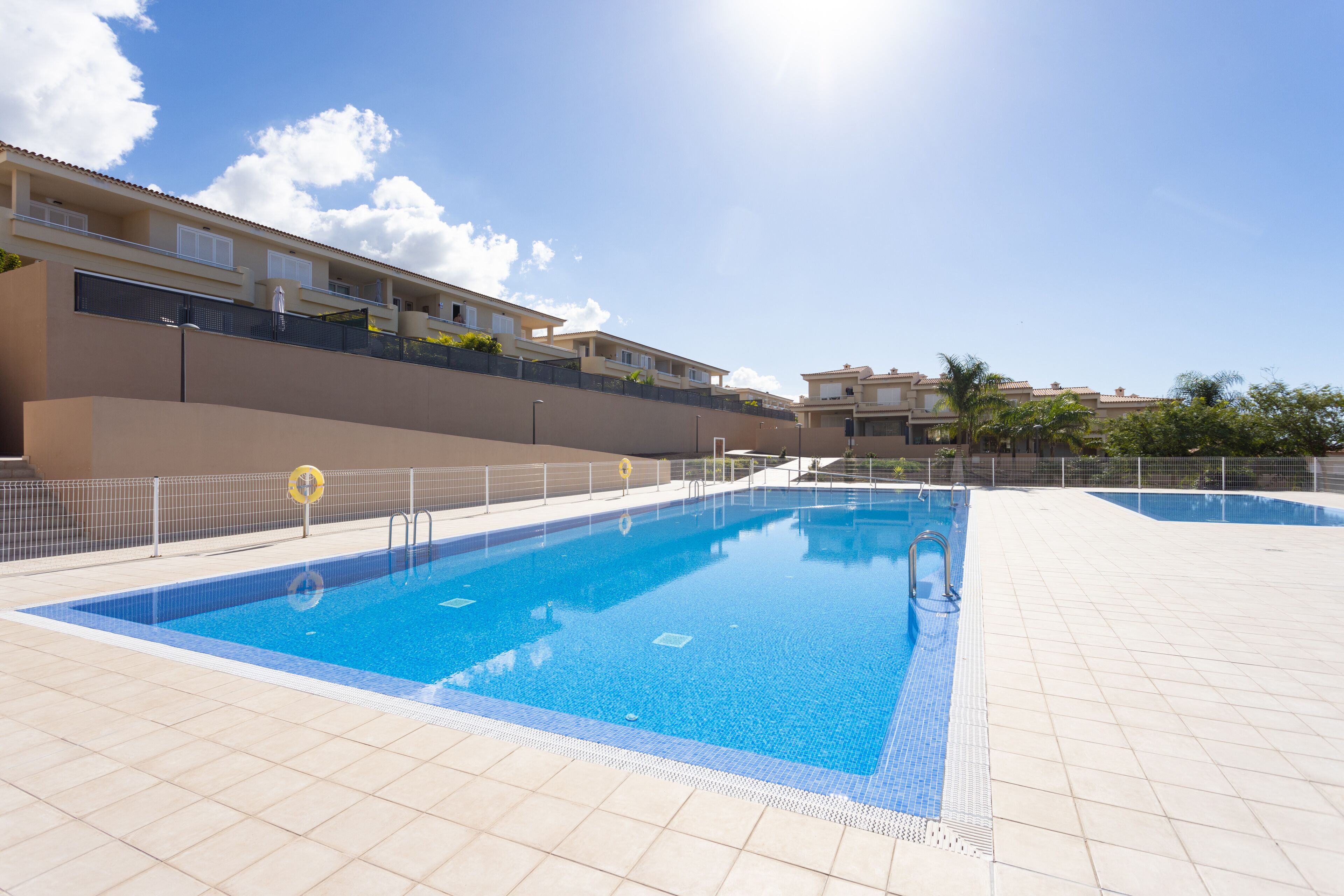 A swimming pool with a tiled deck, a lifeguard stand, and a fence.