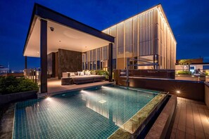 A modern hotel with a rooftop infinity pool, a covered outdoor seating area, and a large building with vertical lines. - The Rixx MarQ (Ho Chi Minh City)