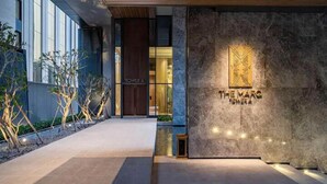 Una entrada de hotel moderna con fachada de piedra y un cartel que dice "THE MARG TOWER A".