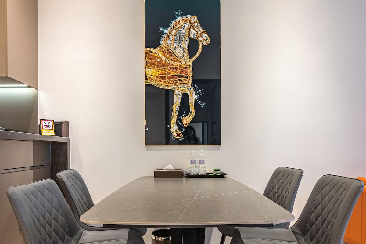 A modern dining area with a dark grey table and black chairs with gold accents. A large abstract artwork hangs on the wall above the table.