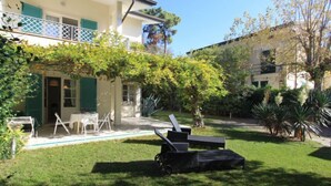 A two-story house with a balcony, a lawn, and outdoor furniture. - Villa Glicine by Interhome (Forte dei Marmi)