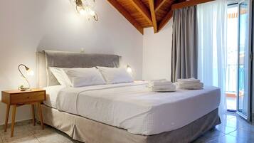 Quarto com cama, luminárias de cabeceira, mesa de cabeceira e vista para o exterior através de uma janela.