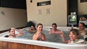 A group of people in a hot tub with a sign reading "Pool" on the wall.