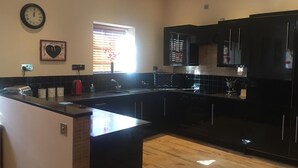 A modern kitchen with black cabinetry, a central island, and a clock on the wall.