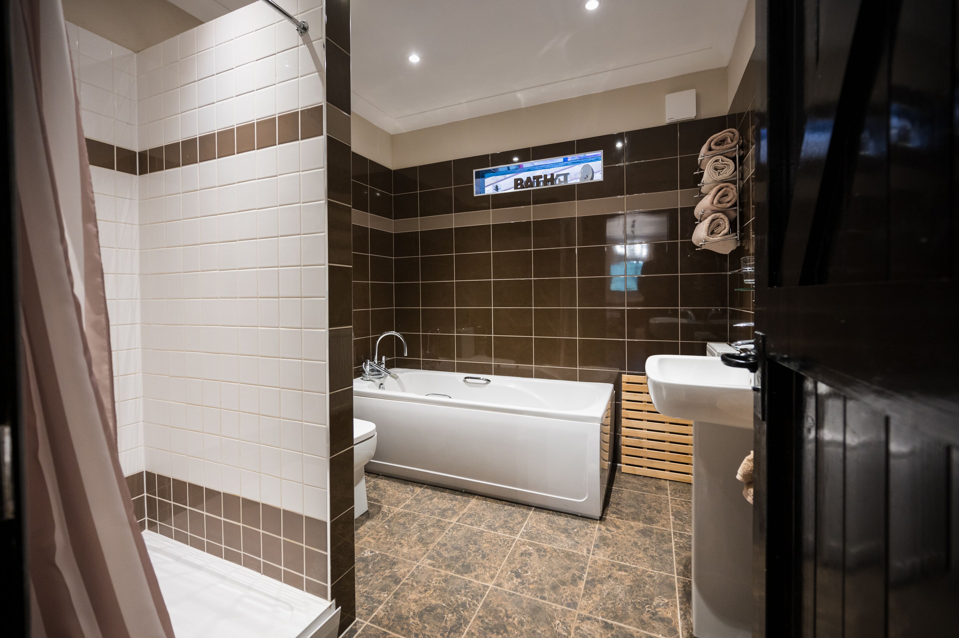 A modern bathroom with a bathtub, a toilet, and a shower area.