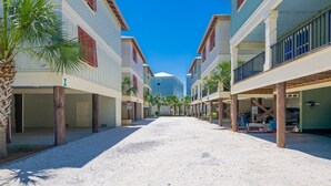 Uma rua estreita com edifícios de ambos os lados, uma palmeira e um céu azul claro.