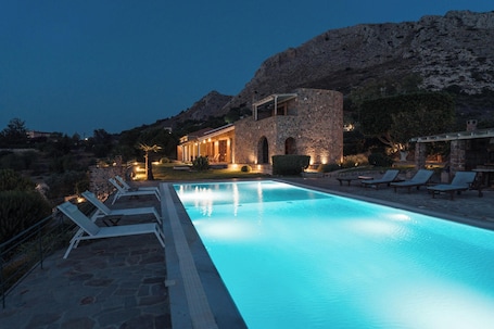 Una piscina al aire libre, sombrillas, sillones reclinables de piscina