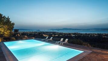 Relax by the serene pool surrounded by a patio, overlooking the ocean and the city.