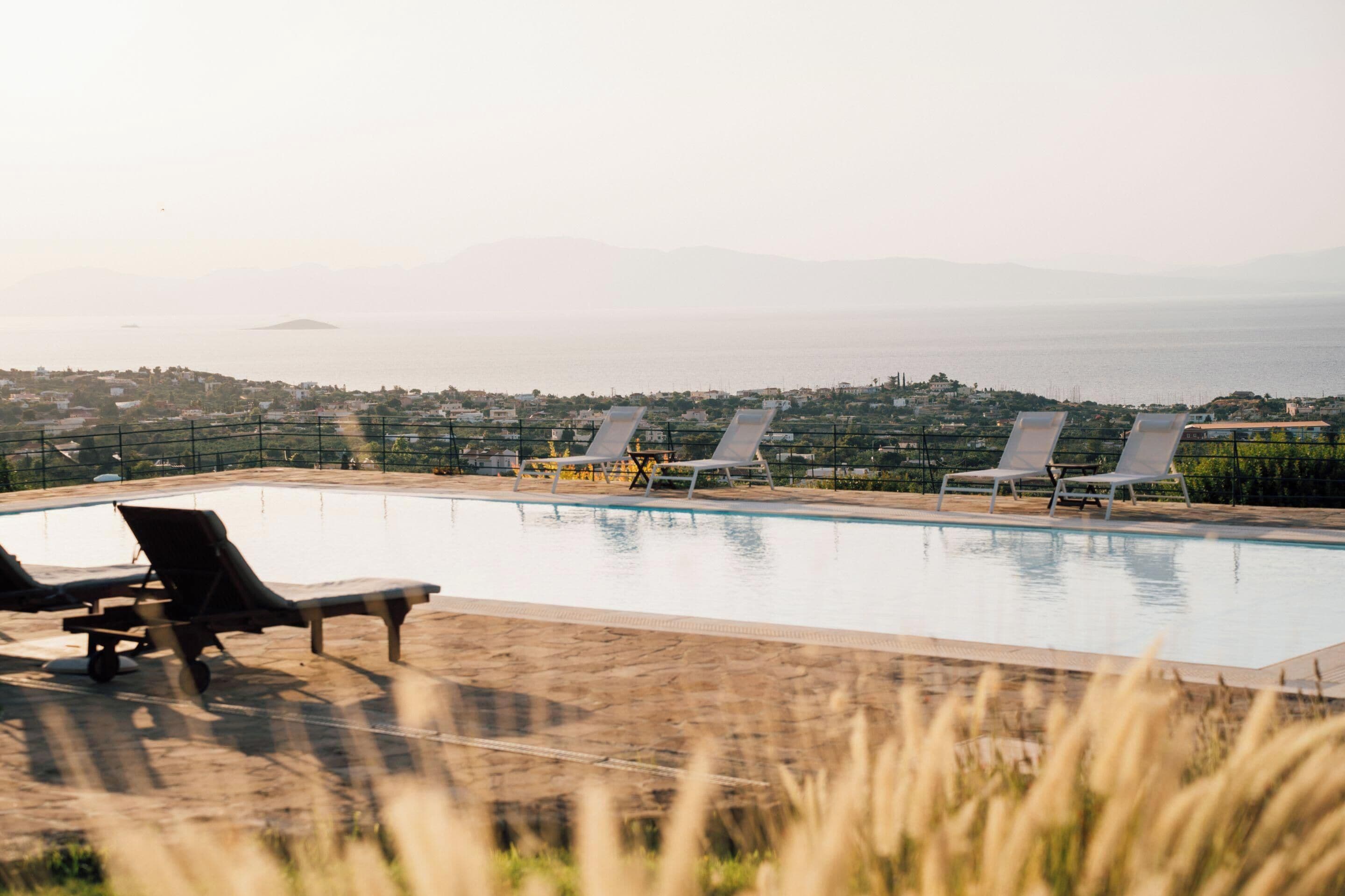 Una piscina al aire libre, sombrillas, sillones reclinables de piscina