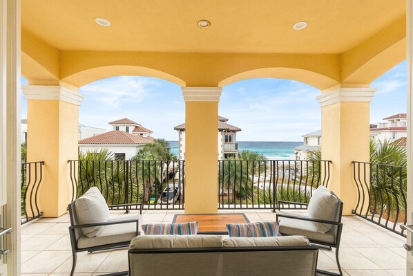 A balcony with a view of the ocean, featuring a sofa and a table.