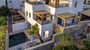 A modern multi-story building with balconies, a swimming pool, and a view of the surrounding area. - Clementina Paros (Paros)