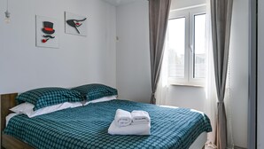 Een opgemaakt bed met een stippenbedekking, twee kussens en een paar opgevouwen handdoeken op het bed.