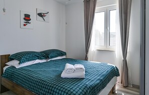 A neatly made bed with a polka dot bedspread, two pillows, and a pair of folded towels on the bed.