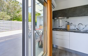 A modern kitchen with a gas stove, stainless steel sink, and white cabinets. - Beautiful home in Peroj with WiFi (Peroj)
