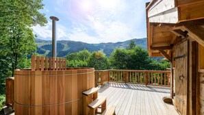 A wooden deck with a sauna, benches, and a view of mountains. - Gorgeous, truly ski-in ski-out chalet with hot tub, sauna, fabulous views (Les Allues)