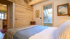 A bedroom with a bed, wooden walls, a skylight, and a painting. - Gorgeous, truly ski-in ski-out chalet with hot tub, sauna, fabulous views (Les Allues)