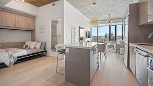 Un appartement moderne comprenant une grande cuisine, un coin repas, un salon et une chambre.