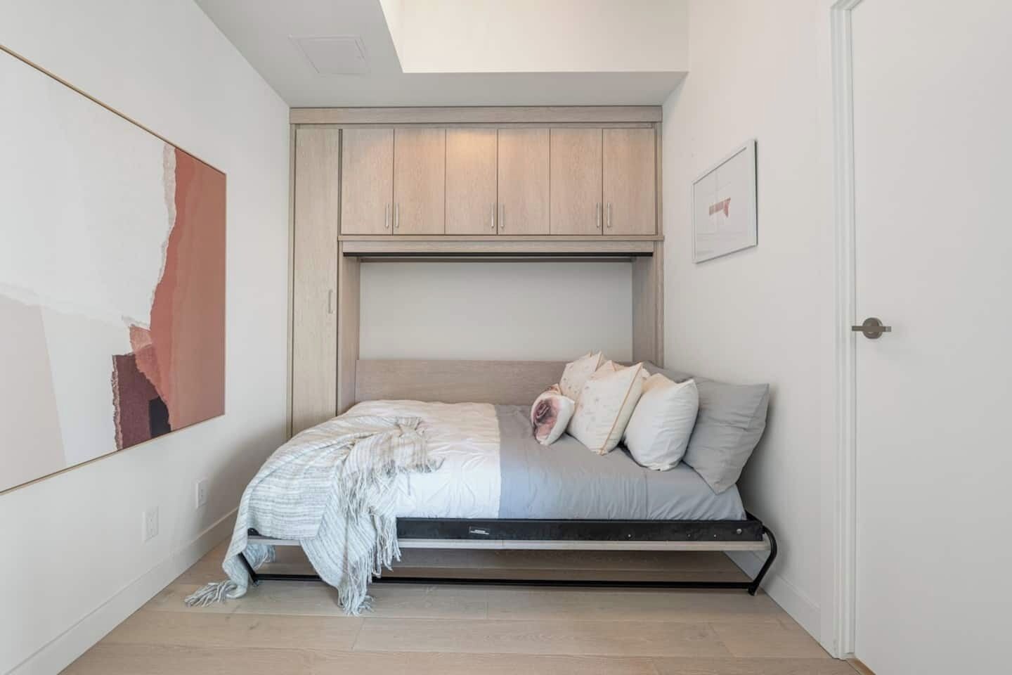 A bedroom with a bed, a headboard, a door, and a ceiling light.