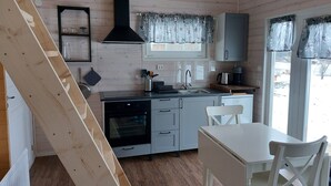 A compact kitchen with a stove, sink, and a window with curtains. - Swedish-style guest house in the beautiful nature and tranquillity of central Sweden. (Stöde)