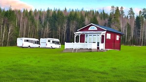 A red building with a white porch and a covered entrance, surrounded by a grassy field and a forest. - Swedish-style guest house in the beautiful nature and tranquillity of central Sweden. (Stöde)