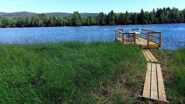 A wooden dock extending into a lake with a forested shoreline. - Swedish-style guest house in the beautiful nature and tranquillity of central Sweden. (Stöde)
