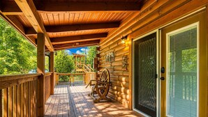Una terraza de madera con techo de madera, una rueda grande de madera y un gran ventanal corredero.