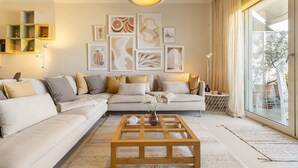A living room with a sectional sofa, a coffee table, and artwork on the wall. - Something special in Chalkida - 300 m from the seafront (Xirovrisi)