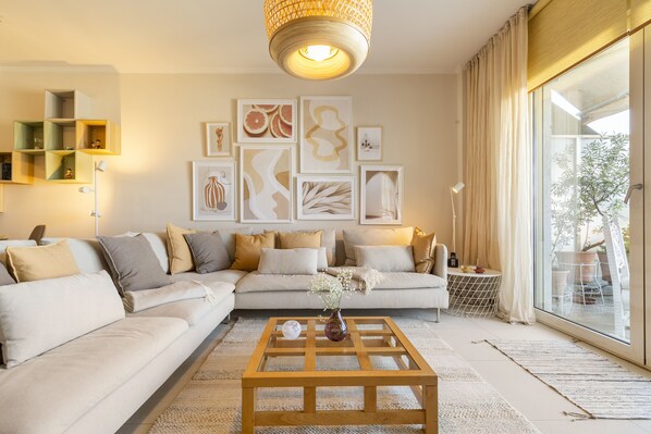 Ein Wohnzimmer mit einem Ecksofa, einem Couchtisch und Kunstwerken an der Wand.