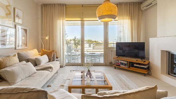 A living room with a sofa, coffee table, TV, and a large window with curtains. - Something special in Chalkida - 300 m from the seafront (Xirovrisi)