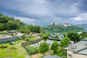 A view of a lake surrounded by lush greenery and buildings, including a bridge over the water. - Nicewalk B&B (Yuchi)
