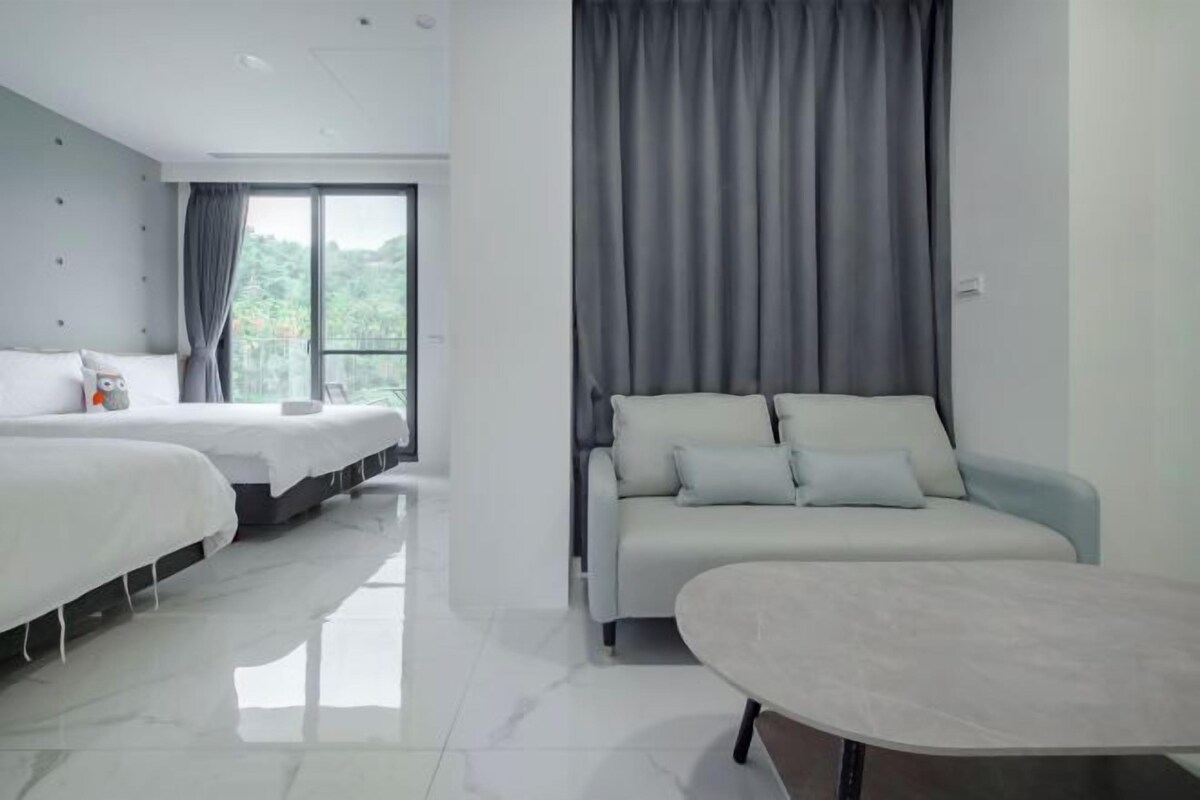 A modern hotel room with a large bed, a sofa, and a small table.