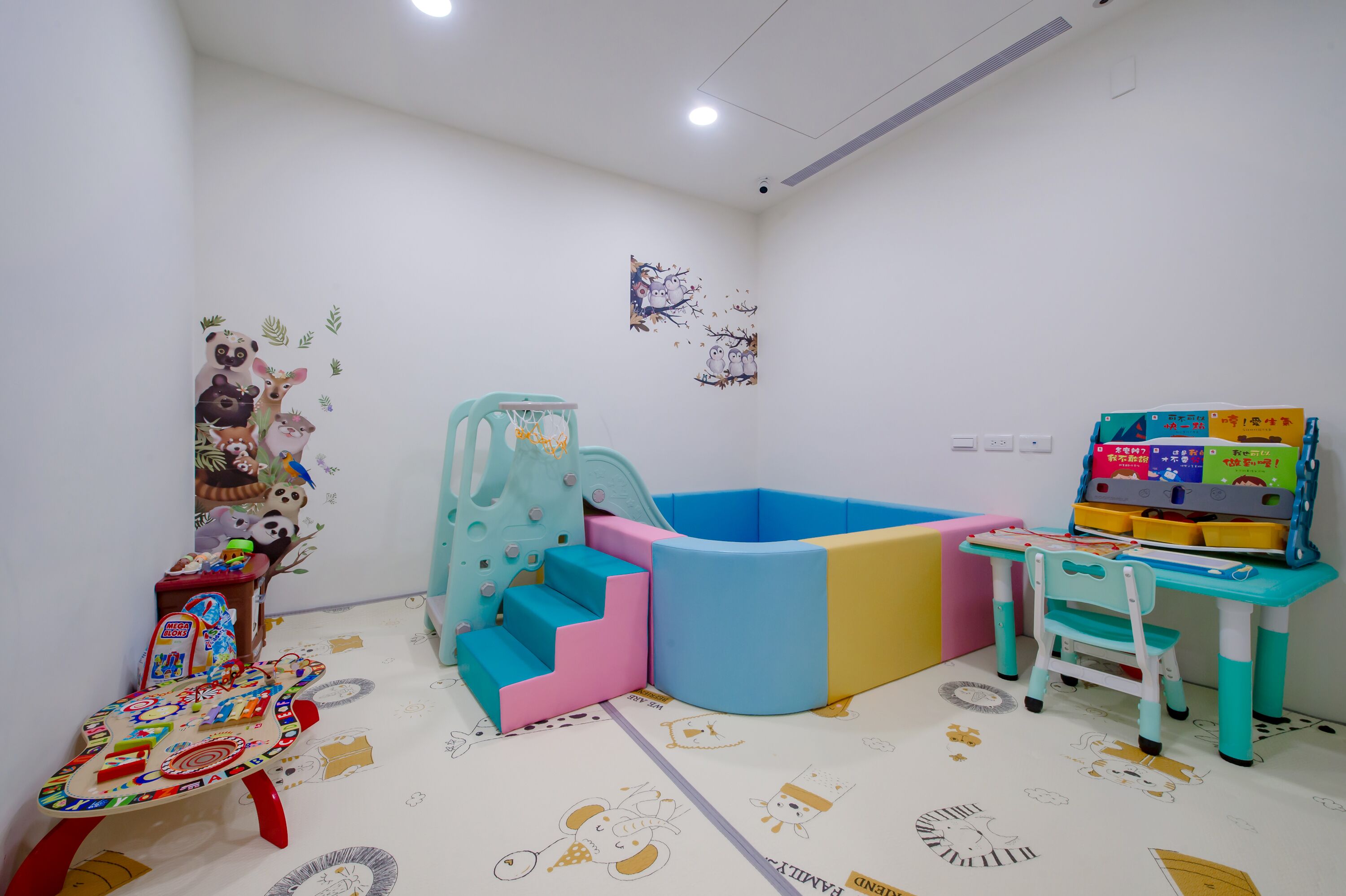 A children's play area with a soft play structure, a small table with toys, and a chair.