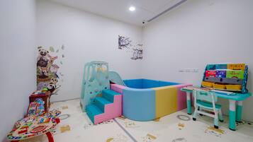 A children's play area with a soft play structure, a small table with toys, and a chair.