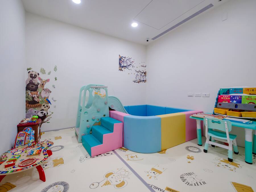 A children's play area with a soft play structure, a small table with toys, and a chair.