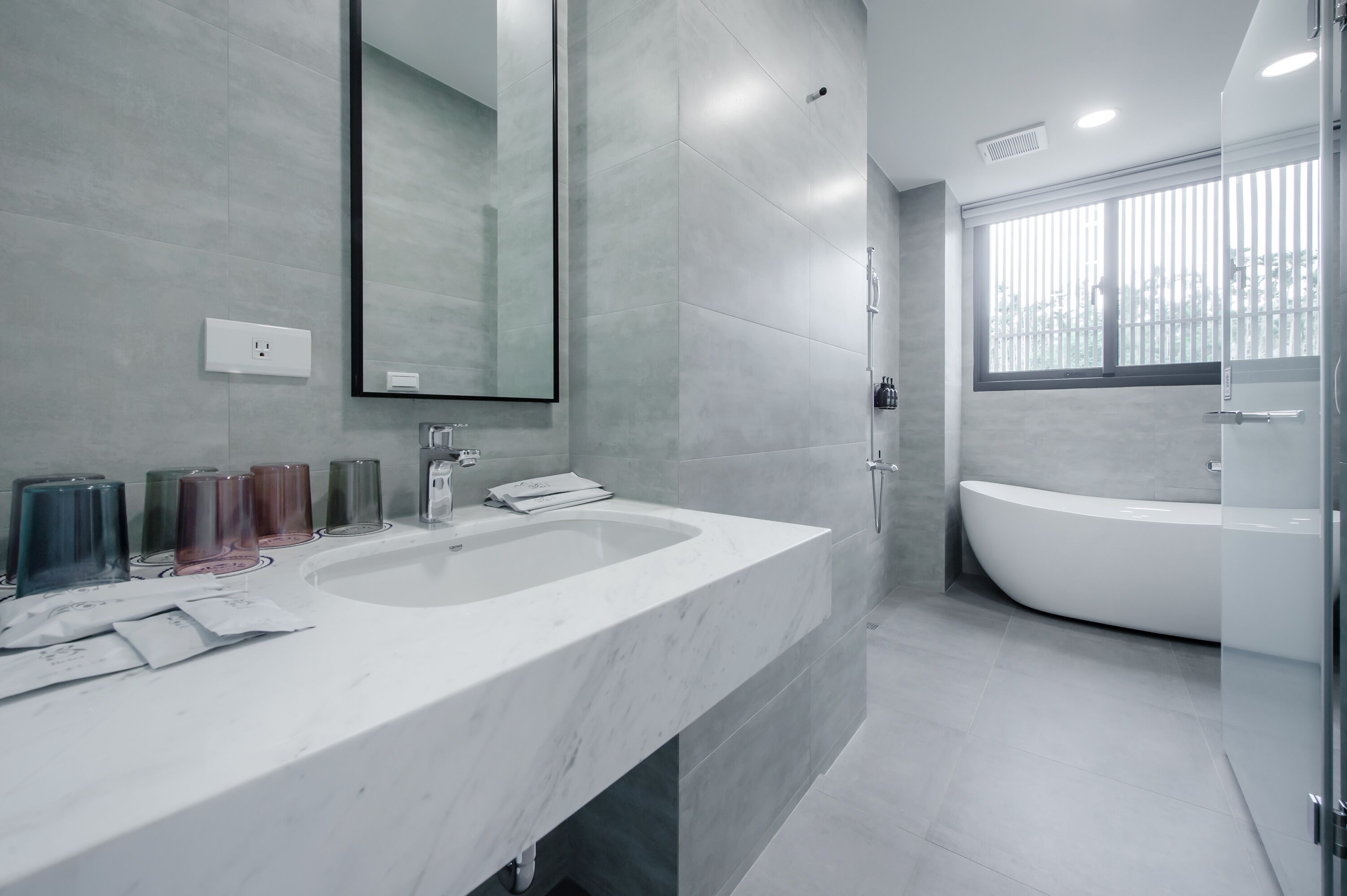 Un baño moderno con dos lavamanos, un espejo grande y una bañera independiente.