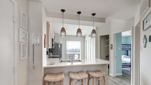 A modern kitchen with a white countertop, three wicker bar stools, and pendant lighting. - Salty Moose | 2BD Close To Whitecap Beach | Pool (Corpus Christi)