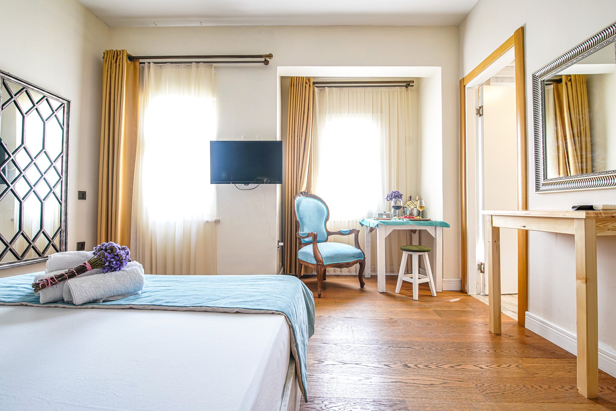 A hotel room with a bed, a desk, a chair, a television, and a mirror.
