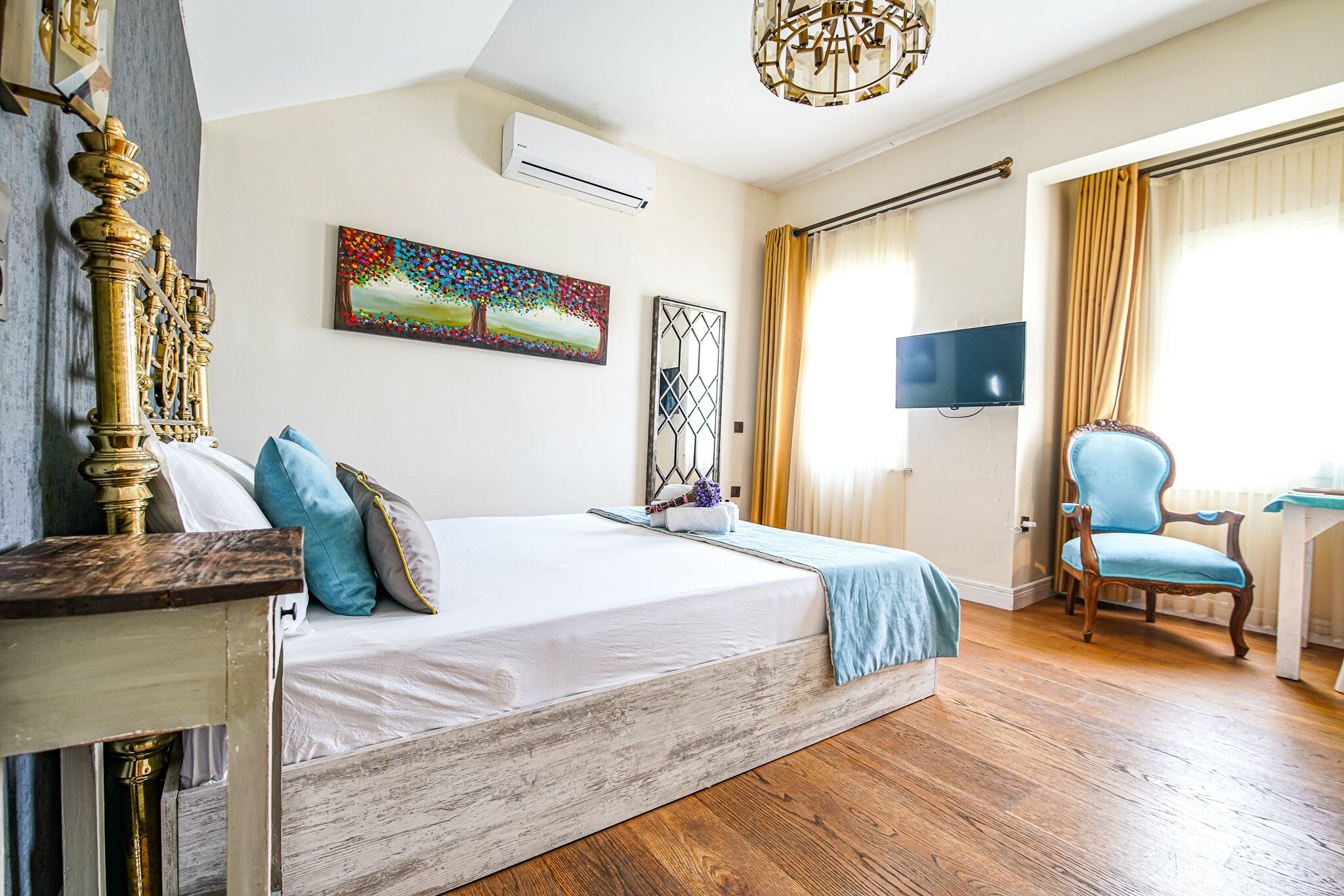 A bedroom with a bed, a chair, a desk, a TV, and a painting on the wall.