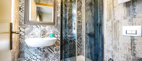A bathroom with a curved shower enclosure, a sink, and a toilet.